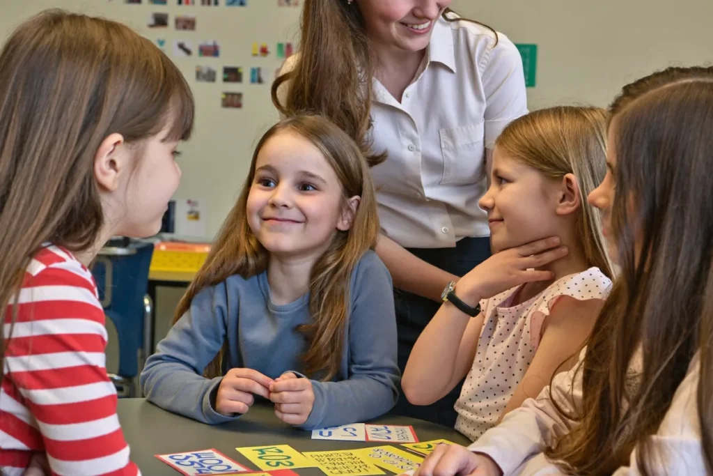 Profesoară încurajând cald un copil timid să vorbească într-o grupă mică de engleză